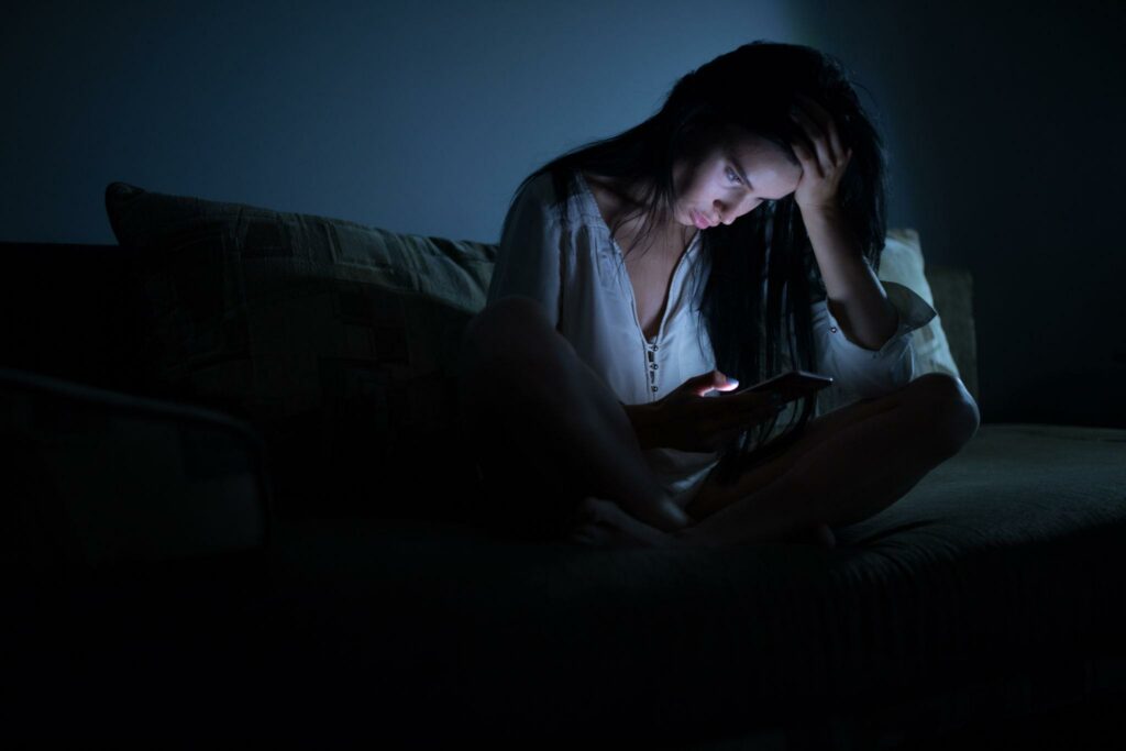 Who Owns Our Conversations? Probably Not Us. tired woman using blue smartphone screen at night dark room